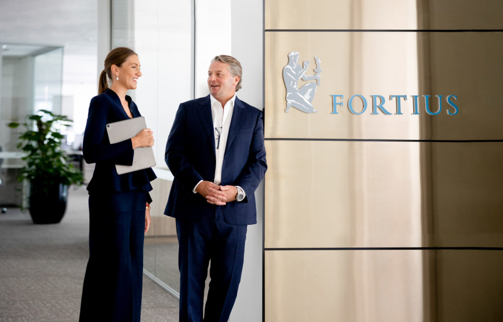 Team standing beside company Fortius logo