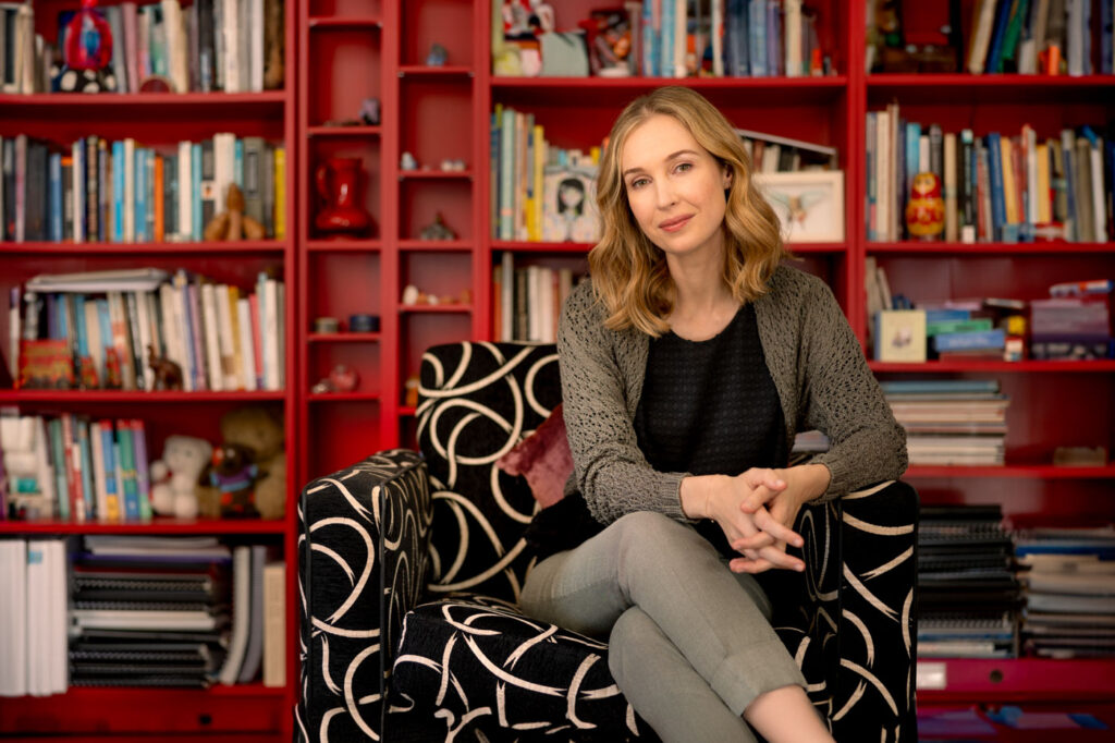 Psychologist sitting in front of red bookshelf